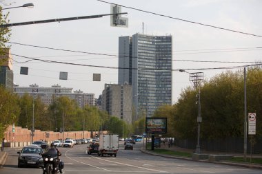 MOSCOW / RUSSIA - 20 / 04 / 2019 Konyushkovskaya Ulitsa Caddesi 'nin bahar günü çekimleri, insanlar yürüyor, arabalar yolda, yeşil ağaçlar, binalar ve çitler etrafında