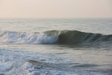 Ufukta mavi gökyüzü olan beyaz köpük oluşturan, pürüzsüz sarı kumsal yüzeyine çarpan bir dalganın doğal fotokopi uzay görüntüsü. Sabahın erken saatlerinde Pitiwella sahilinde, Sri Lanka
