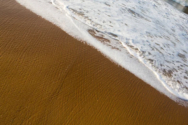 美しいフレームを閉じます海の壁紙の背景はかなりテクスチャとパターンを形成するインド海の白い泡の波と黄金のオレンジの砂のショット スリランカのPitiwellaビーチ — ストック写真