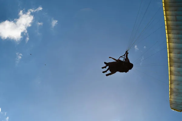 晴れた日に雲を背景に青い空を背景にパラグライダーで飛び立つ少女のシルエット — ストック写真