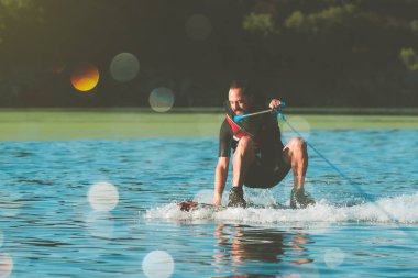 Sakallı genç hippi nehirde sörf yapıyor.