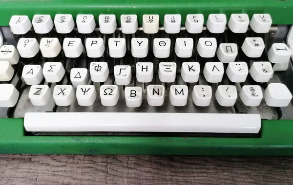 木製のテーブルの上にギリシャ文字と古い緑のタイプライター — ストック写真