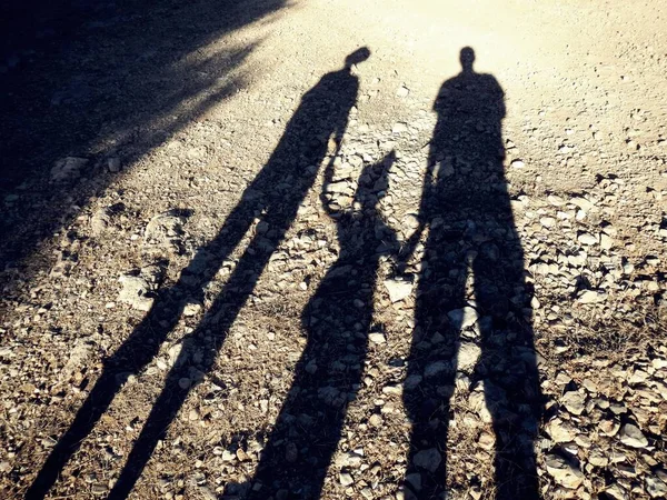 A family is depicted on the ground by the shadows of it's members.