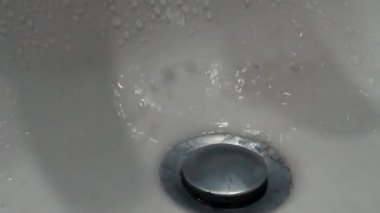 Kirli bir musluktan kirli bir lavaboya akan su. Kamera lavabodan musluğa dikey olarak hareket ediyor. 60 fps 'te yüksek çözünürlüklü görüntü.