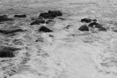Taşların arasından denize su geliyor. siyah ve beyaz çekim.