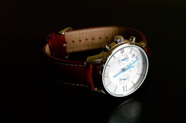 Güzel lüks bir adamın kol saati mavi saat elleri ve siyah arka planda kahverengi deri kayışı var.