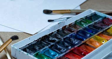 Beyaz kağıt üzerinde suluboya ve fırçalar.