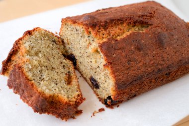 Kuru üzümlü ve çay yapraklı siyah çay tereyağlı kek. Beyaz arka planı olan tahta bir kesme tahtasının üzerinde dilimlenmiş. Pastanenin güzel kokulu manzarası ve pastanenin dokusunun makro görüntüsü.