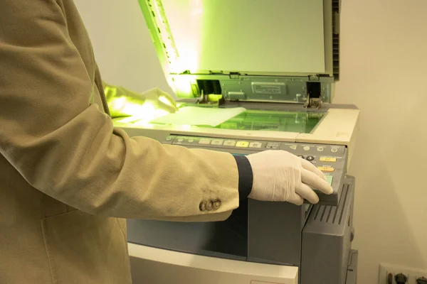 Man making copies with the copy machine in the office with gloves to protect from coronavirus