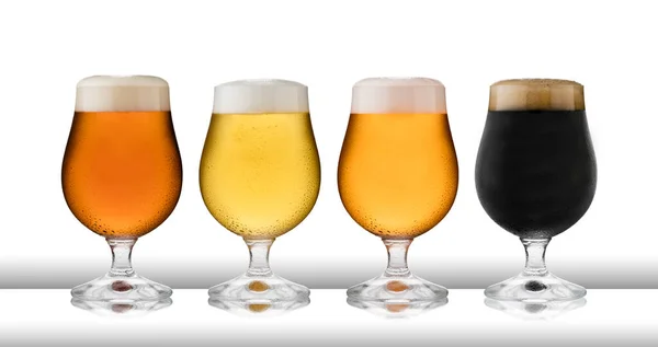 Dört bardak ferahlatıcı bira, bira, elma şarabı ve bira, ıskarmoz gözlükleriyle, yoğuşma, beyaz masa üstü ve beyaz arka planda.