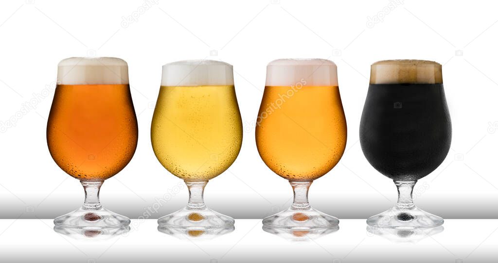 Four glasses of refreshing lager, beer, cider and stout, in  schooner glasses, with condensation, on a white table top and white background