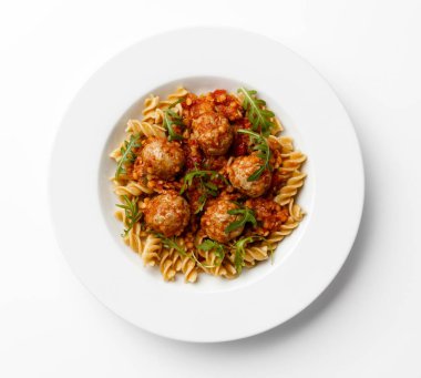 Beyaz bir arka planda, beyaz bir tabakta bir roket garnitürlü domates soslu köfte..