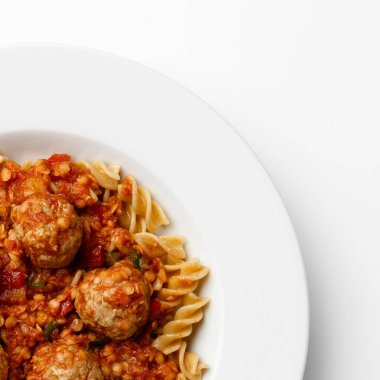 Domates soslu köfte tabağının köşesinde, beyaz bir arka planda, salça kıvrımlı..