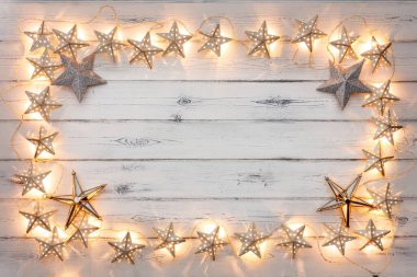 Bir dizi altın yıldız noel ışıkları, ve yıldız mücevherleri, basık ahşap arka planda, kopya için boş bir alan etrafında bir sınır oluşturur.