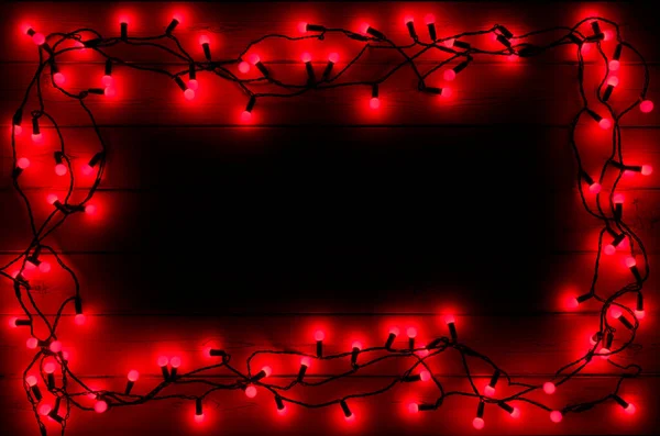 Bir dizi kırmızı Holly Berryr Noel ışıkları, karanlık bir ahşap arka planda, kopya için boş bir alan etrafında bir sınır yaratıyor.
