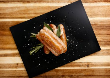 Baharatlı lezzetli sosisler, sarımsak ve otlu garnitür, tahta tabakta.