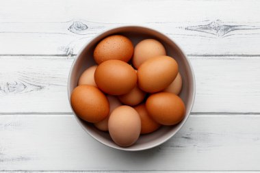 Kasede taze yumurta, sıkıntılı beyaz ahşap arka planda.