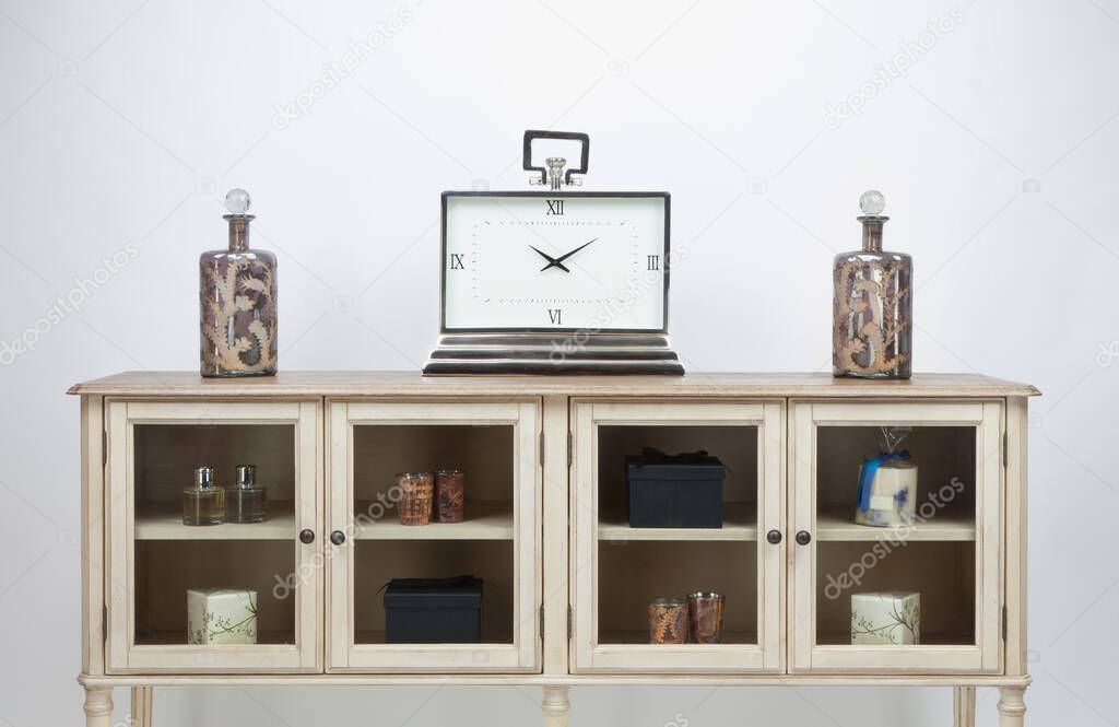 Glass fronted sideboard and ornaments and a large clock on a white background