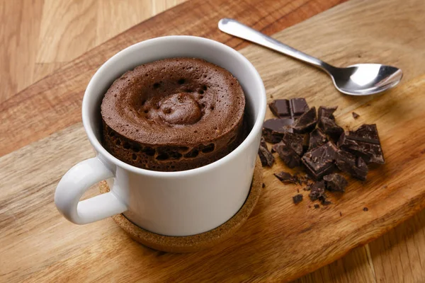 美味的巧克力海绵布丁 用一只装满软糖碎片的手 用勺子放在木板上 倒入一杯 — 图库照片