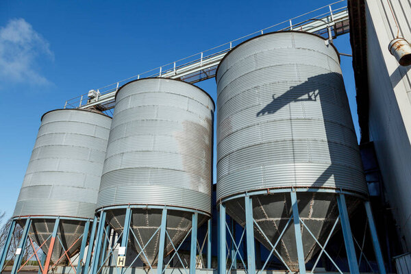 3 Grain silos, in an industrial landscape, with a beautiful blue sky