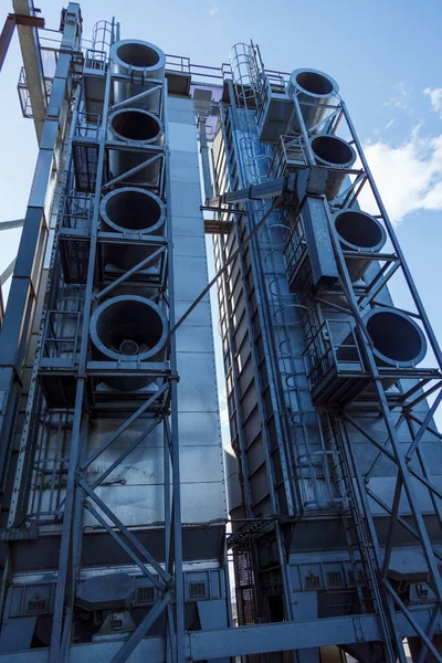 Industrial grain cereal drying machine with huge circular air vents, and a blue sky