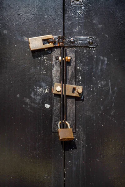 錆びた南京錠と古い暗い金属製のドアのロックバー — ストック写真