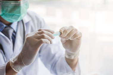 Sağlık ekibi Coronavirus Covid-19 'u incelemek ve salgını durdurmak için Coronavirus Covid-19 aşısını araştırmak için bir koronavirüs koruyucu giysisi ve lastik eldiven giydi..