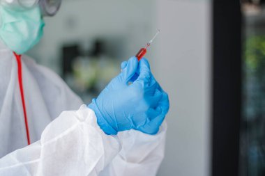 Sağlık ekibi Coronavirus Covid-19 'u incelemek ve salgını durdurmak için Coronavirus Covid-19 aşısını araştırmak için bir koronavirüs koruyucu giysisi ve lastik eldiven giydi.