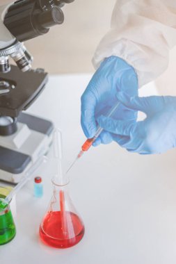 Sağlık ekibi Coronavirus Covid-19 'u incelemek ve salgını durdurmak için Coronavirus Covid-19 aşısını araştırmak için bir koronavirüs koruyucu giysisi ve lastik eldiven giydi.