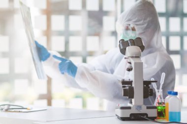 Sağlık ekibi Coronavirus Covid-19 'u incelemek ve salgını durdurmak için Coronavirus Covid-19 aşısını araştırmak için bir koronavirüs koruyucu giysisi ve lastik eldiven giydi..