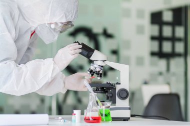 Sağlık ekibi Coronavirus Covid-19 'u incelemek ve salgını durdurmak için Coronavirus Covid-19 aşısını araştırmak için bir koronavirüs koruyucu giysisi ve lastik eldiven giydi..