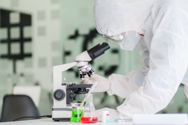 Sağlık ekibi Coronavirus Covid-19 'u incelemek ve salgını durdurmak için Coronavirus Covid-19 aşısını araştırmak için bir koronavirüs koruyucu giysisi ve lastik eldiven giydi..