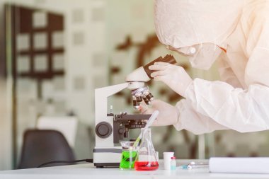 Sağlık ekibi Coronavirus Covid-19 'u incelemek ve salgını durdurmak için Coronavirus Covid-19 aşısını araştırmak için bir koronavirüs koruyucu giysisi ve lastik eldiven giydi..