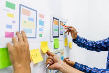 Web sitesi tasarımcılarından oluşan bir ekip, akıllı telefonun ön tarafındaki ux ui sistemi ile görüntüleme biçimini belirlemek için programlar yazıyorlar ve katman oluşturuyorlar..