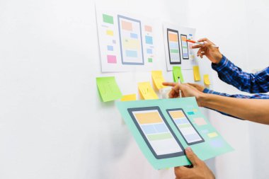 Web sitesi tasarımcılarından oluşan bir ekip, akıllı telefonun ön tarafındaki ux ui sistemi ile görüntüleme biçimini belirlemek için programlar yazıyorlar ve katman oluşturuyorlar..