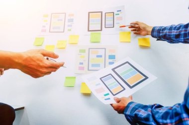 Web sitesi tasarımcılarından oluşan bir ekip, akıllı telefonun ön tarafındaki ux ui sistemi ile görüntüleme biçimini belirlemek için programlar yazıyorlar ve katman oluşturuyorlar..