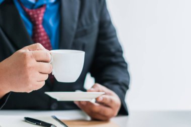 Görüntü bulanık, evin dışındaki manzarayı görmek için evdeki cam kenarındaki sandalyede kahve yudumlayan ve işe başlamadan önce kahve molası veren bir adam. Ev kavramından çalışmaya devam et