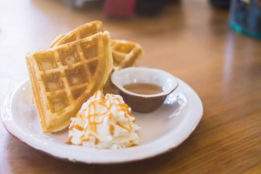 Pürüzsüz Odaklanma ve Bulanık Görüntüler, Waffle ve Akçaağaç şurubu beyaz bir tabağa konur ve krema üzerine tat katmak için krema konur..