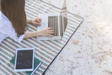 Yumuşak Odak, arka bahçesindeki yerde tek başına çalışan genç bir kadın bilgisayarını kullanarak kablosuz ağ üzerinden bilgi ve tavsiyelerde bulunuyor. Evden çalışma kavramı.