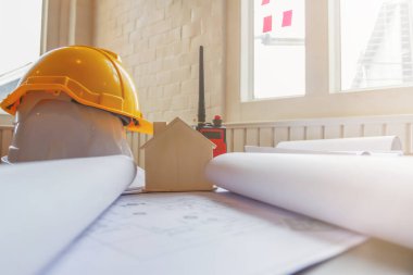 Mühendislerin ve mimarların masası planlar, kırtasiye malzemeleri ve bilgisayarlarla dolu. Ekipman, kırtasiye malzemeleri, bir sürü belge ve mühendisin masasına yerleştirilmiş bir kask..