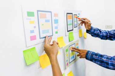 Web sitesi tasarımcılarından oluşan bir ekip, akıllı telefonun ön tarafındaki ux ui sistemi ile görüntüleme biçimini belirlemek için programlar yazıyorlar ve katman oluşturuyorlar..