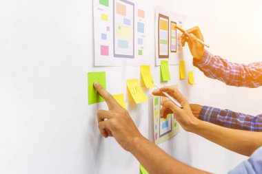 Web sitesi tasarımcılarından oluşan bir ekip, akıllı telefonun ön tarafındaki ux ui sistemi ile görüntüleme biçimini belirlemek için programlar yazıyorlar ve katman oluşturuyorlar..