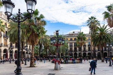 Placa Rejal, palmiyeler tarafından gölgelendirilmiş ve bir çeşme tarafından soğutulmuş. Merkezde Gaud olarak bilinen renkli lamba direkleri var. Barselona, İspanya.