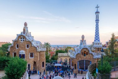 Parc Guell, arka planda şehrin bulunduğu ana girişin renkli binaları. Barselona, İspanya.