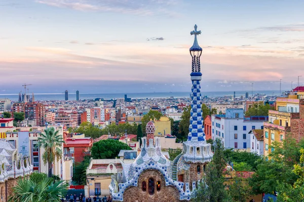 Barselona, İspanya - 02 Kasım 2018: Gün batımında Park Guell 'den Barcelona' nın görüntüsü. Ön planda ana girişin renkli binalarından biri. Barselona, İspanya.