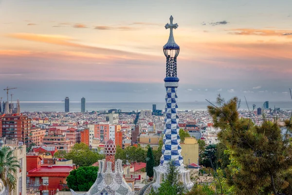 Gün batımında Park Guell 'den Barselona manzarası. Ön planda, ana giriş binasının renkli çatısının detayları var. Barselona, İspanya.