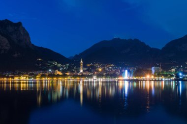Lecco 'nun gece manzarası Como Gölü' ne yansıyor. Arka planda dağlar, İtalya.
