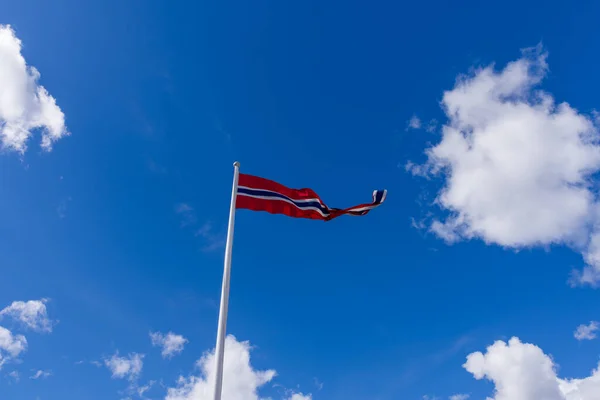 Mavi gökyüzünde dalgalanan Norveç bayrağı ve beyaz bulutlar