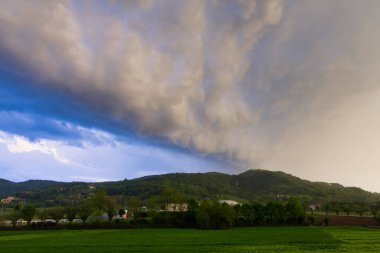 Yeşil tepede fırtına öncesi tehditkar bulutlar