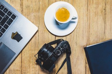 Kameralı tahta masa masası, dizüstü bilgisayar, hafıza kartları, espresso bardağı ve dosya. Yukarıdan görüntüle.